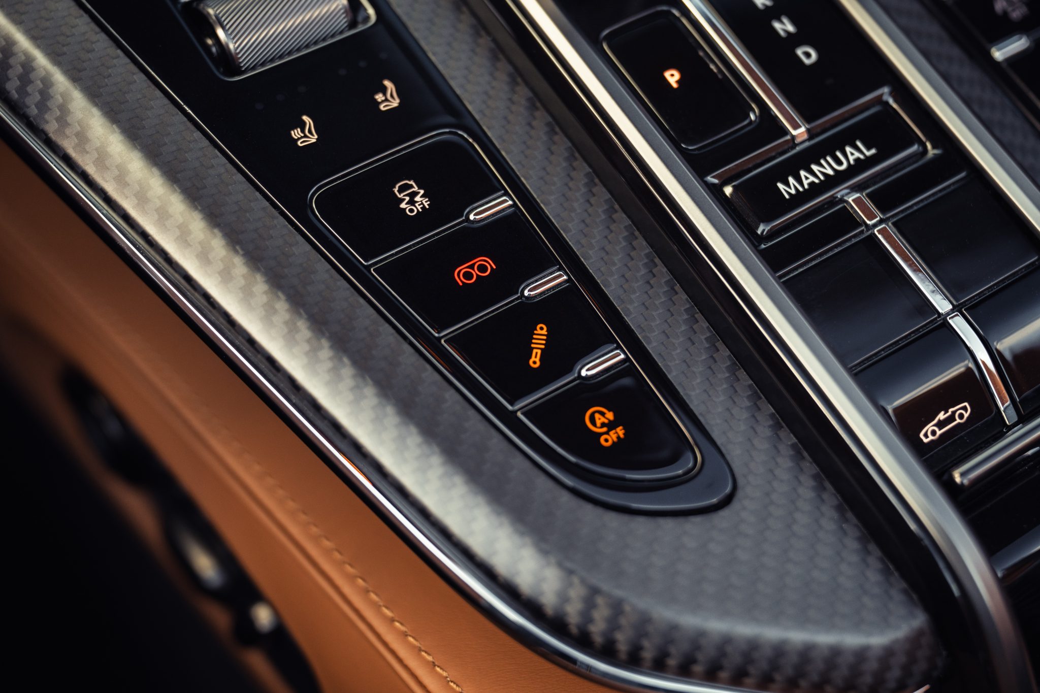 2026 Aston Martin Vantage Roadster interior buttons for the suspension and exhaust, surrounded by matte carbon fiber
